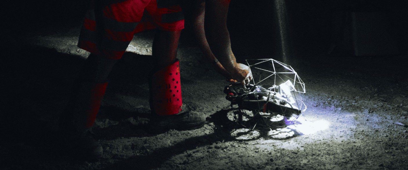 Flyability Elios 3 Inspektionsdrohne mit Schutzkäfig und LED Beleuchtung wird im dunklen Kanal für den Einsatz vorbereitet