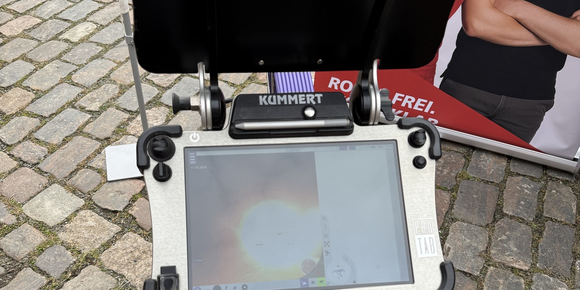 Kamerasteuerung von Kummert mit laufendem Monitorbild aus einem Rohr, aufgebaut auf dem Kopfsteinpflaster beim Messestand