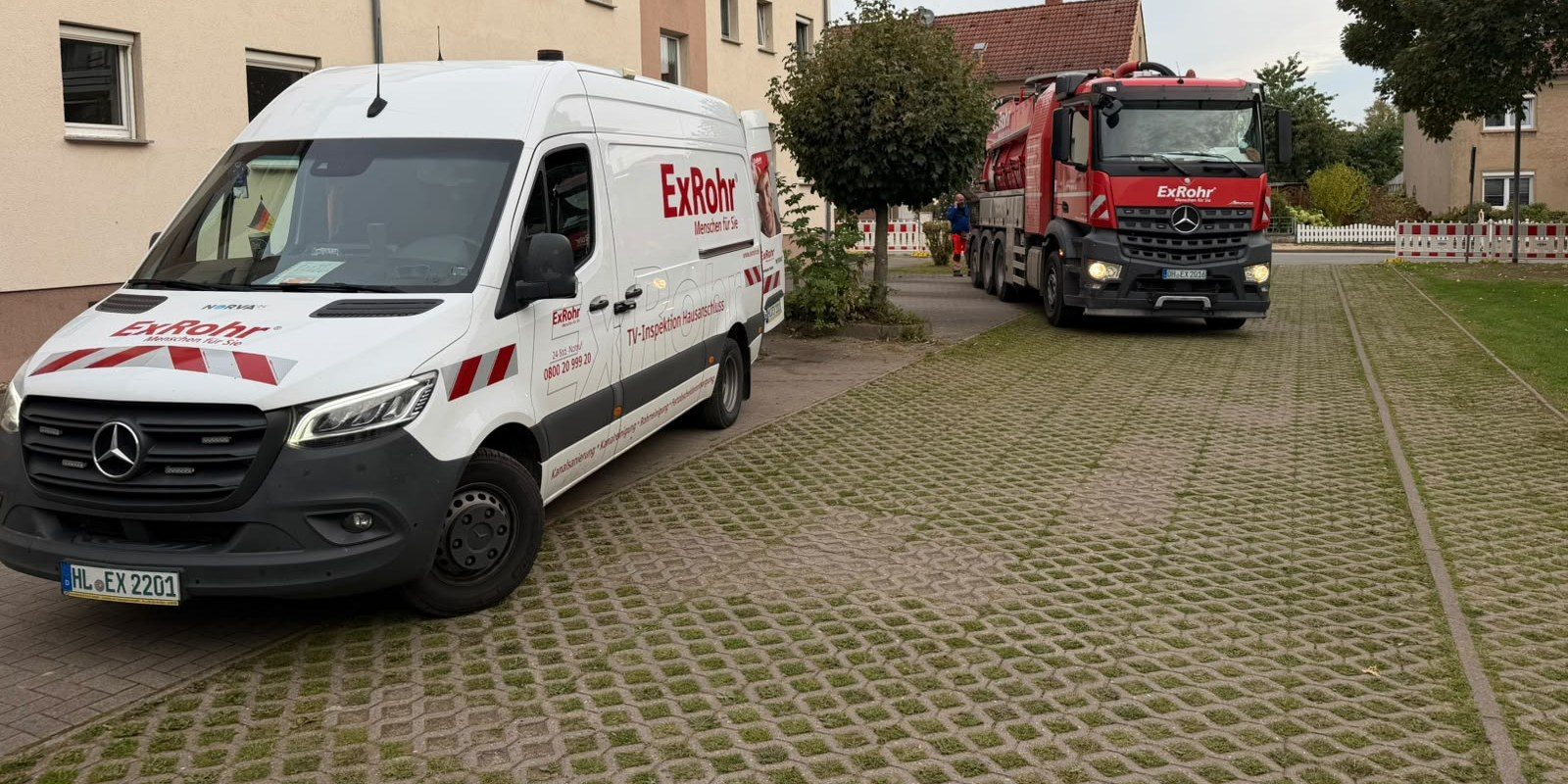 TV-Transporter und Saugwagen von ExRohr vor einer Wohnanlage